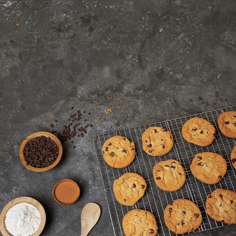 A baking tray with cookies and a bowl of flour